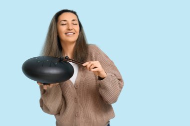 Güzel olgun bir kadın mavi arka planda glukofon çalıyor.