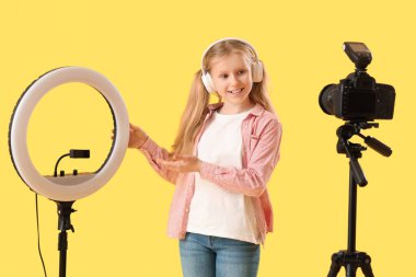 Kulaklıklı genç blogcu sarı arka planda video kaydediyor