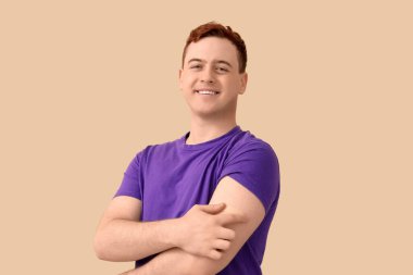 Bej arka planda uygulamalı tıbbi yaması olan mutlu genç bir adam. Aşılama kavramı