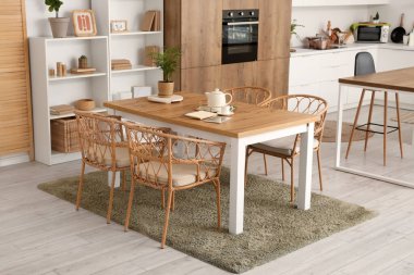 Yemek masası ve raf üniteleri olan rahat mutfağın içi.