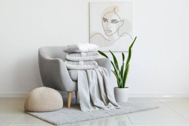 Beyaz duvarın yanında yastık yığını olan gri koltuk