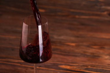 Ahşap zemin üzerinde lezzetli kırmızı şarap bardağına dökülüyor