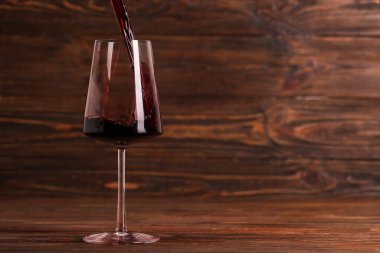 Ahşap zemin üzerinde lezzetli kırmızı şarap bardağına dökülüyor
