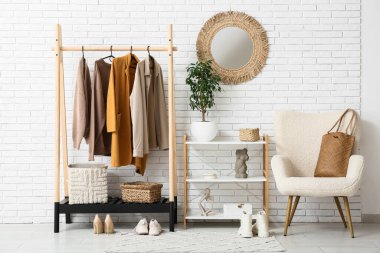 Koridorun içinde koltuk, ayna ve şık kıyafetler var.