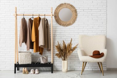 Koridorun içinde koltuk, ayna ve şık kıyafetler var.