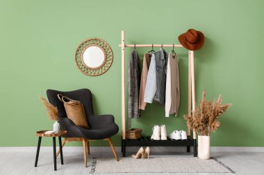 Koridorun içinde şık kıyafetler, koltuk ve ayna var.