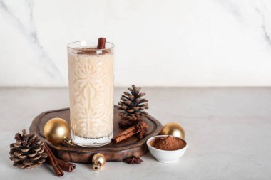 Tarçın, yıldız anason, çam kozalağı ve beyaz arka planda Noel toplarıyla bir bardak nefis eggnog kokteyli.