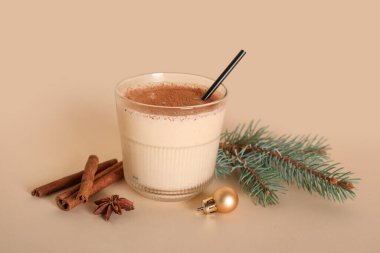 Bir bardak tarçın, yıldız anason, köknar dalı ve sarı arka planda Noel balosuyla nefis bir eggnog kokteyli.