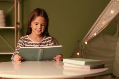 Masada kitap okuyan tatlı küçük kız.