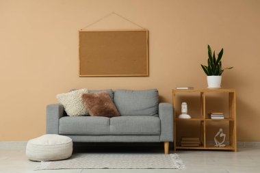 Oturma odasının içinde raflarda eski kitaplar ve bej duvarın yanında kanepe var.