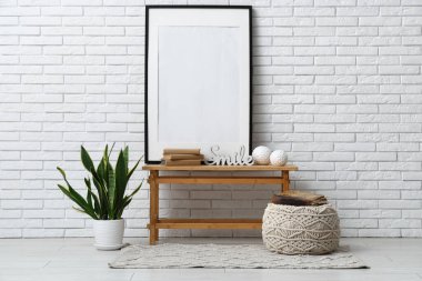 Odadaki beyaz tuğla duvarın yanındaki bankta yığınla eski kitap, resim ve heykel.