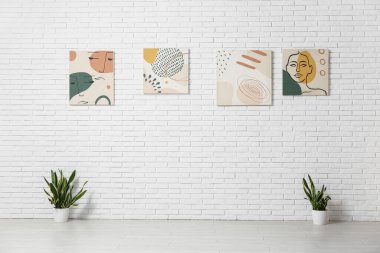 Sanat galerisindeki beyaz tuğla duvarda bitkiler ve güzel tablolar.