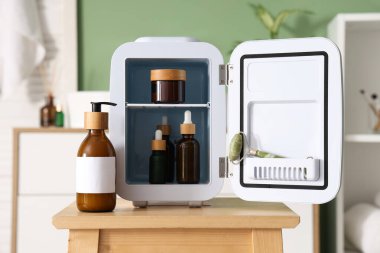 Odadaki yeşil duvara karşı küçük buzdolabı ve kozmetik ürünleri açın. Yakın çekim.