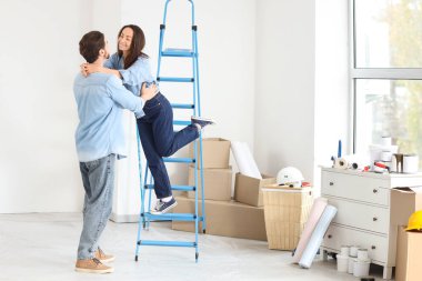 Genç bir kadın yeni evlerinde kocasını kucaklıyor.