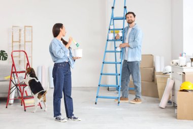 Yeni evlerinde tamirat sırasında boyalı ve köpekli genç bir çift.