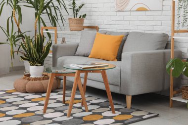 Gri kanepesi, cam sehpası ve çiçekleri olan oturma odasının içinde.