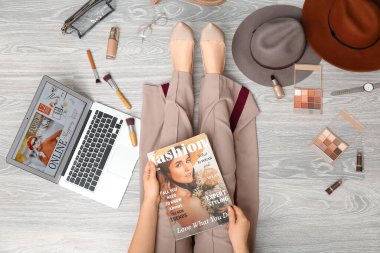 Dergisi olan bir kadın, modern laptop, şık aksesuarlar ve kozmetik ürünler. Çevrimiçi alışveriş kavramı