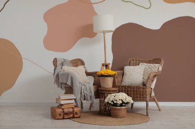 Sıcak hasır koltukları, kasımpatı çiçekleri ve kitapları olan şık bir oturma odası.