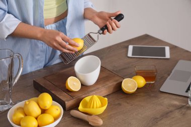 Mutfakta eritilmiş su için limon rendeleyen genç kadın, yakın plan.