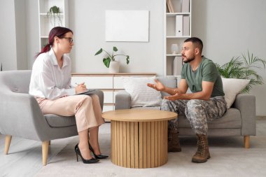 Travma sonrası stres bozukluğu olan erkek asker ofiste psikologla konuşuyor.