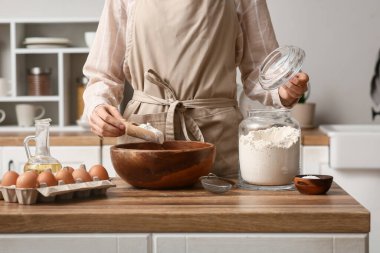 Mutfak tezgahında hamur hazırlamak için kaseye un döken kadın.