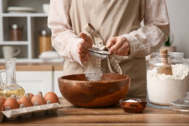 Mutfak tezgahında hamur hazırlamak için unu kaseye karıştıran kadın.