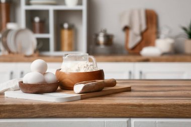 Mutfak tezgahında hamur hazırlamak için bir kase un, kepçe süt ve yumurta.