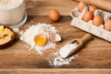 Ahşap zemin üzerinde hamur hazırlamak için un ve yumurta kepçesi.