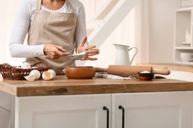 Mutfak tezgahında hamur hazırlamak için unu kaseye karıştıran kadın.