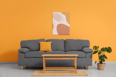 Rahat kanepesi, sehpası ve turuncu duvarın yanındaki çiçekli şık oturma odasının içinde.