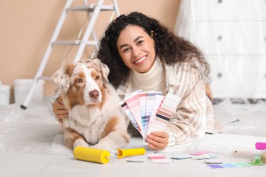 Palet örnekleriyle mutlu bir Afro-Amerikan ressam ve yeni evdeki tamirat sırasında yalan söyleyen tatlı bir Avustralya çoban köpeği.