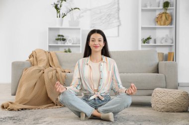 Evinde yerde meditasyon yapan güzel genç bir kadın.