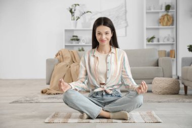Evinde yerde meditasyon yapan güzel genç bir kadın.