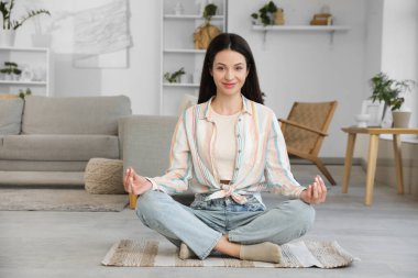 Evinde yerde meditasyon yapan güzel genç bir kadın.