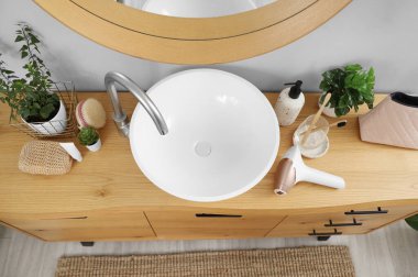 Kozmetik çantalı modern fotoepilatör, diş fırçası ve banyo lavabosunun yanındaki masada bitkiler.