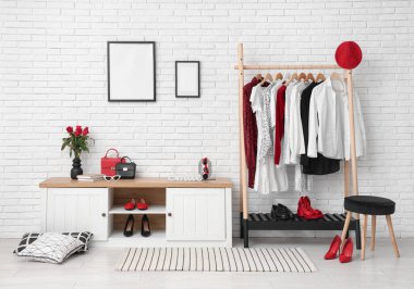 Odada beyaz tuğla duvarın yanında giysi ve büfe var.