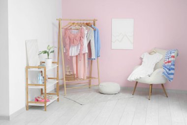 Giysilerle, koltukla ve soyunma odasının içindeki raflarla dolu.