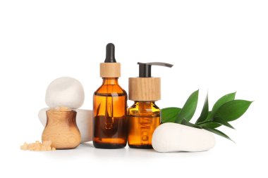 Beyaz arka planda kozmetik ürünleri, spa taşları ve bitki dallarıyla kompozisyon