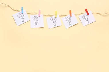 İpte renk arkaplanına asılı soru işaretleri olan yapışkan notlar