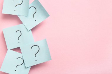Pembe arka planda soru işaretleri olan yapışkan notlar