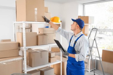 Depodaki raftan karton kutu alan erkek yükleyici.