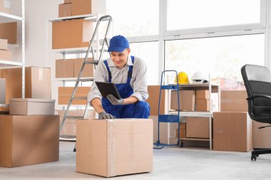 Depoda panosu ve karton kutusu olan bir erkek yükleyici.