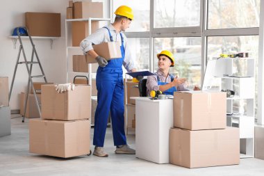 Depoda bilgisayar ve kutularla çalışan erkek yükleyiciler