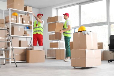 Depoda kutularla çalışan erkek yükleyiciler.