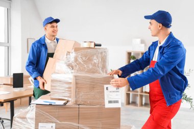 Erkek yükleyiciler ofiste kutuları boşaltıyorlar