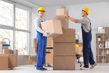 Erkek yükleyiciler ofiste kutu istifliyor.