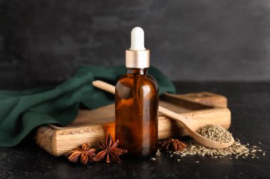 Ahşap tahta tahta, gerekli yağ, kaşık, anason yıldızları ve siyah grunge arka planda kurumuş tohumlar.