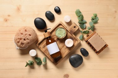 Ahşap zemin üzerinde yanan mumlar ve okaliptüs dallarıyla kaplıca kompozisyonu