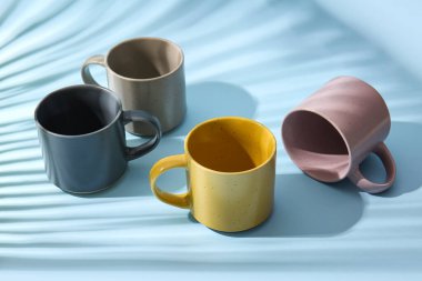 Renkli arka planda gölgeleri olan zarif seramik bardaklar.