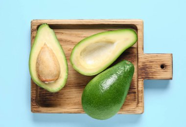 Mavi arka planda taze olgun avokadoları olan ahşap tahta tahta.